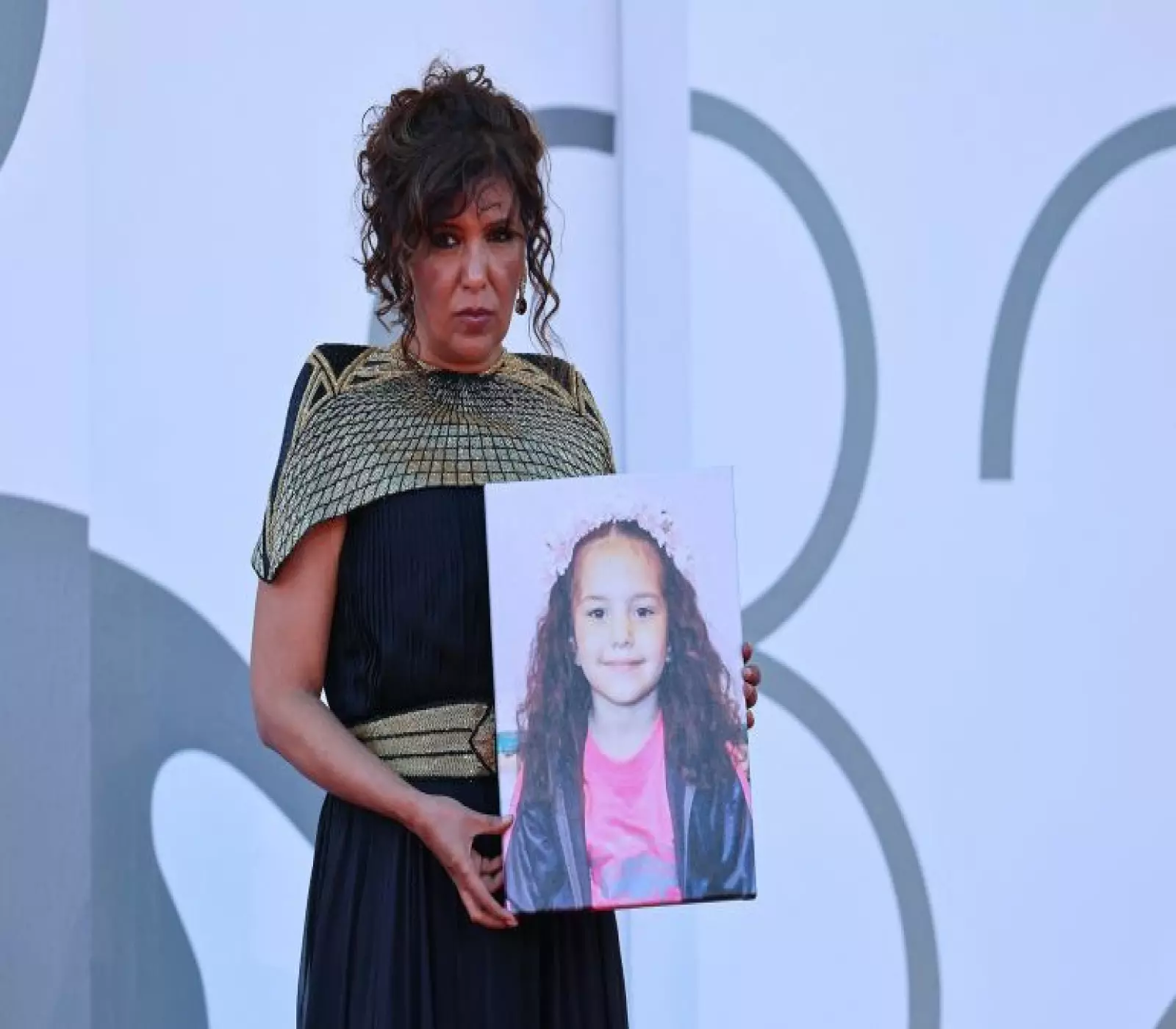 Kaouther Ben Hania poses with a picture of Hind Rajab on the red carpet during arrivals for the screening 'The Voice of Hind Rajab' in competition, at the 82nd Venice Film Festival, Venice, Italy, September 3, 2025. REUTERS/Yara Nardi
