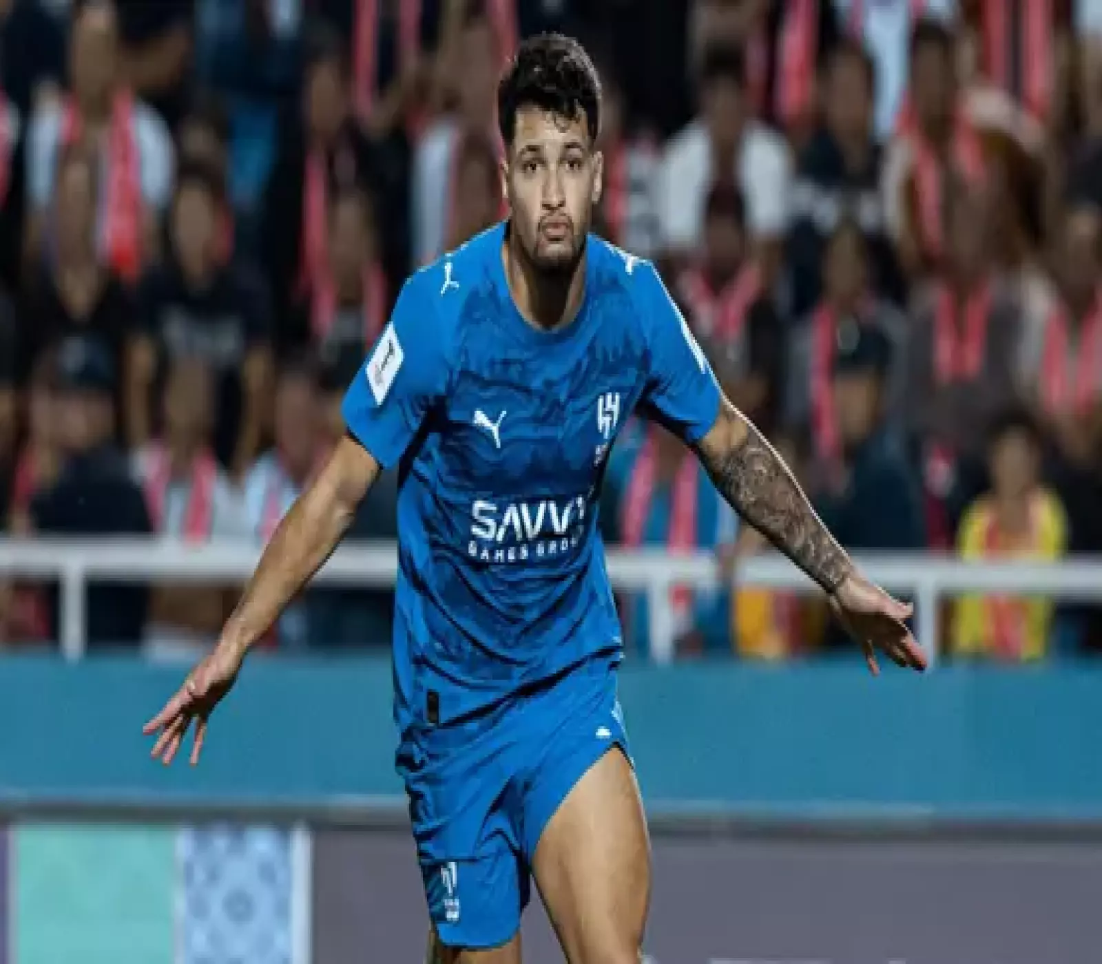 لاعب كرة قدم يرتدي قميص الهلال السعودي الأزرق في الملعب خلال إحدى المباريات.