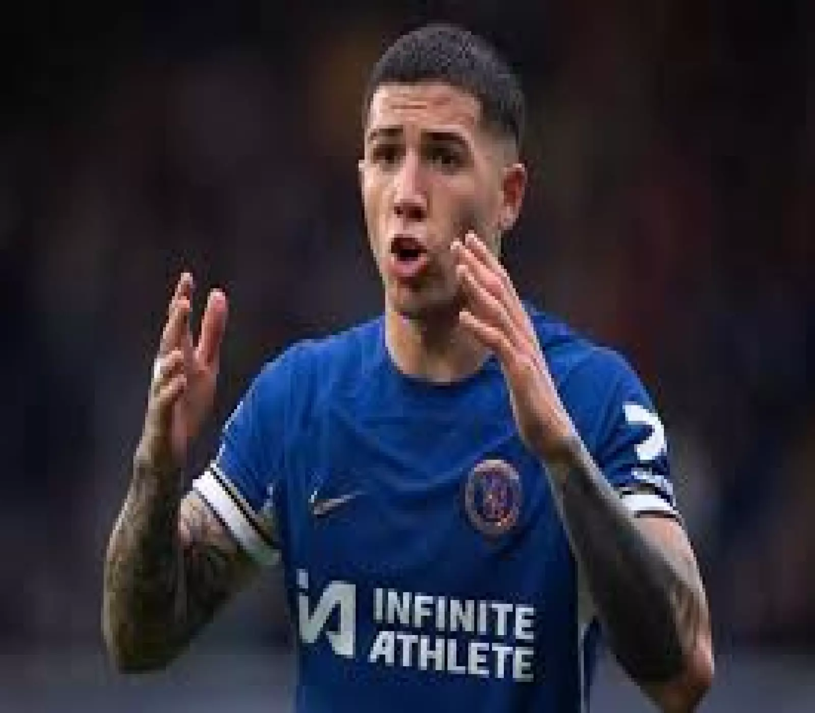 اللاعب إنزو فيرنانديز يرتدي قميص تشيلسي الأزرق ويرفع يديه أثناء مباراة كرة قدم.