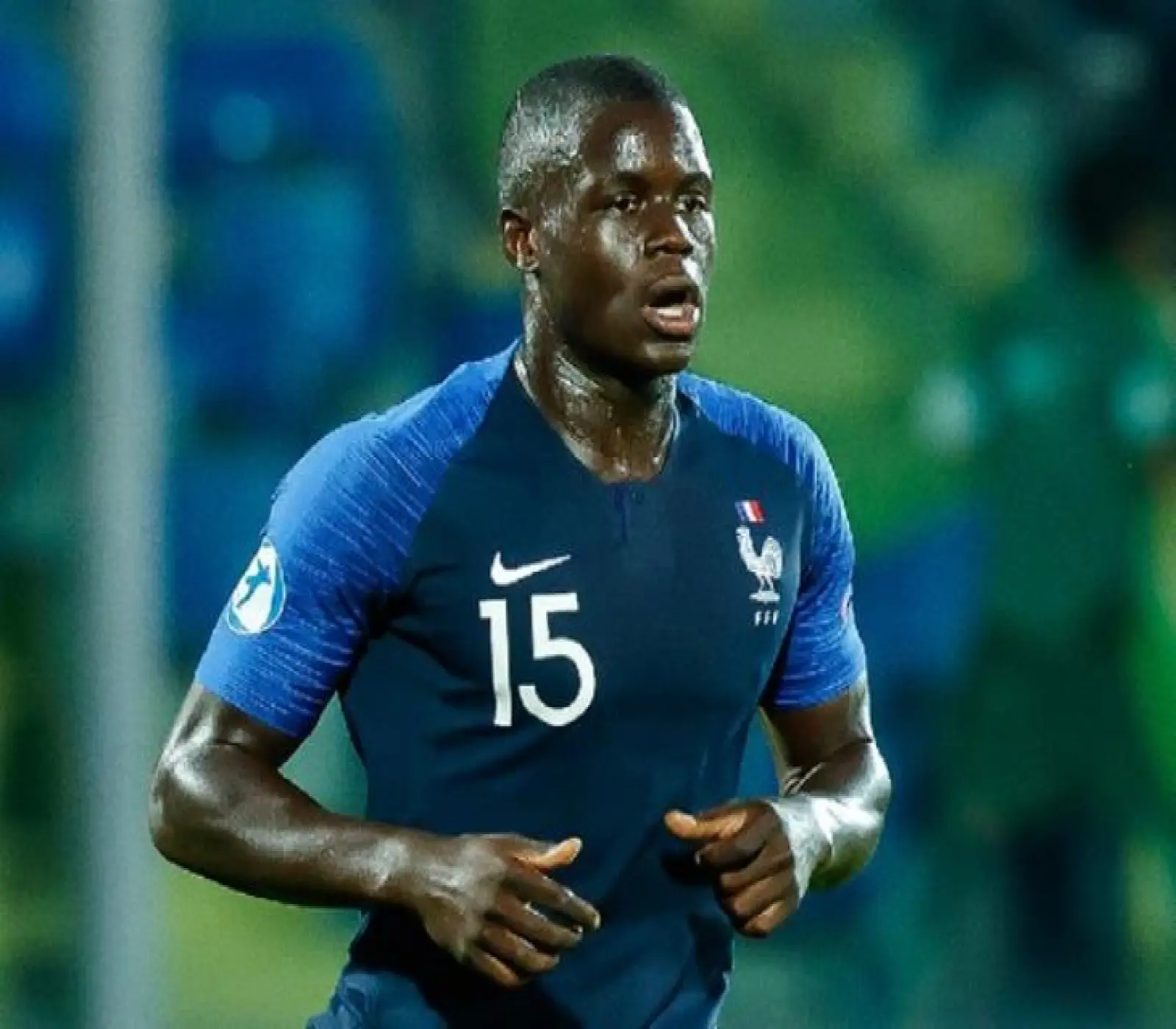 لاعب كرة قدم يرتدي طقم المنتخب الفرنسي الأزرق رقم 15 خلال مباراة ليلية في الملعب.